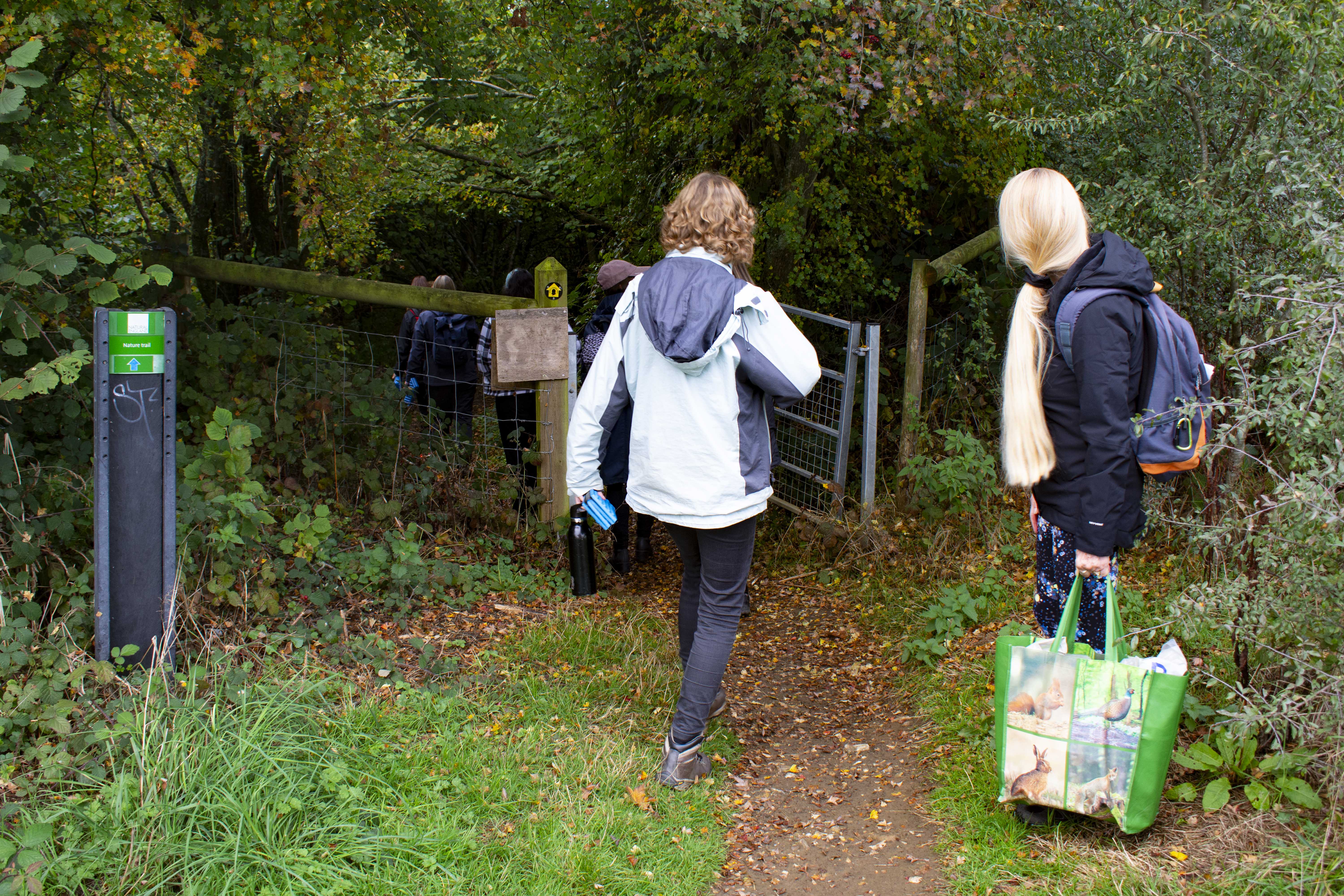 People walking into the entrance of the woods at Wye Nature Reserve.